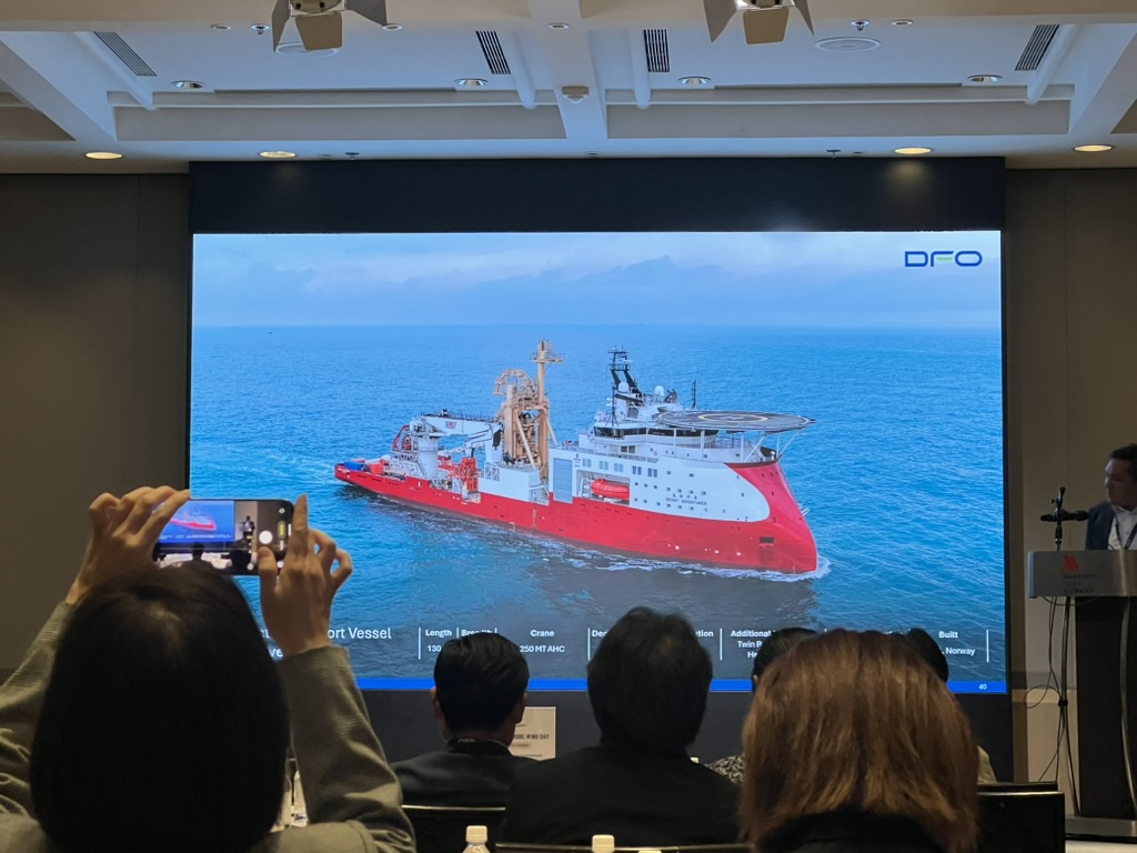 A red offshore support vessel shown on a presentation screen at Asia Offshore Wind Day, photographed from the audience.